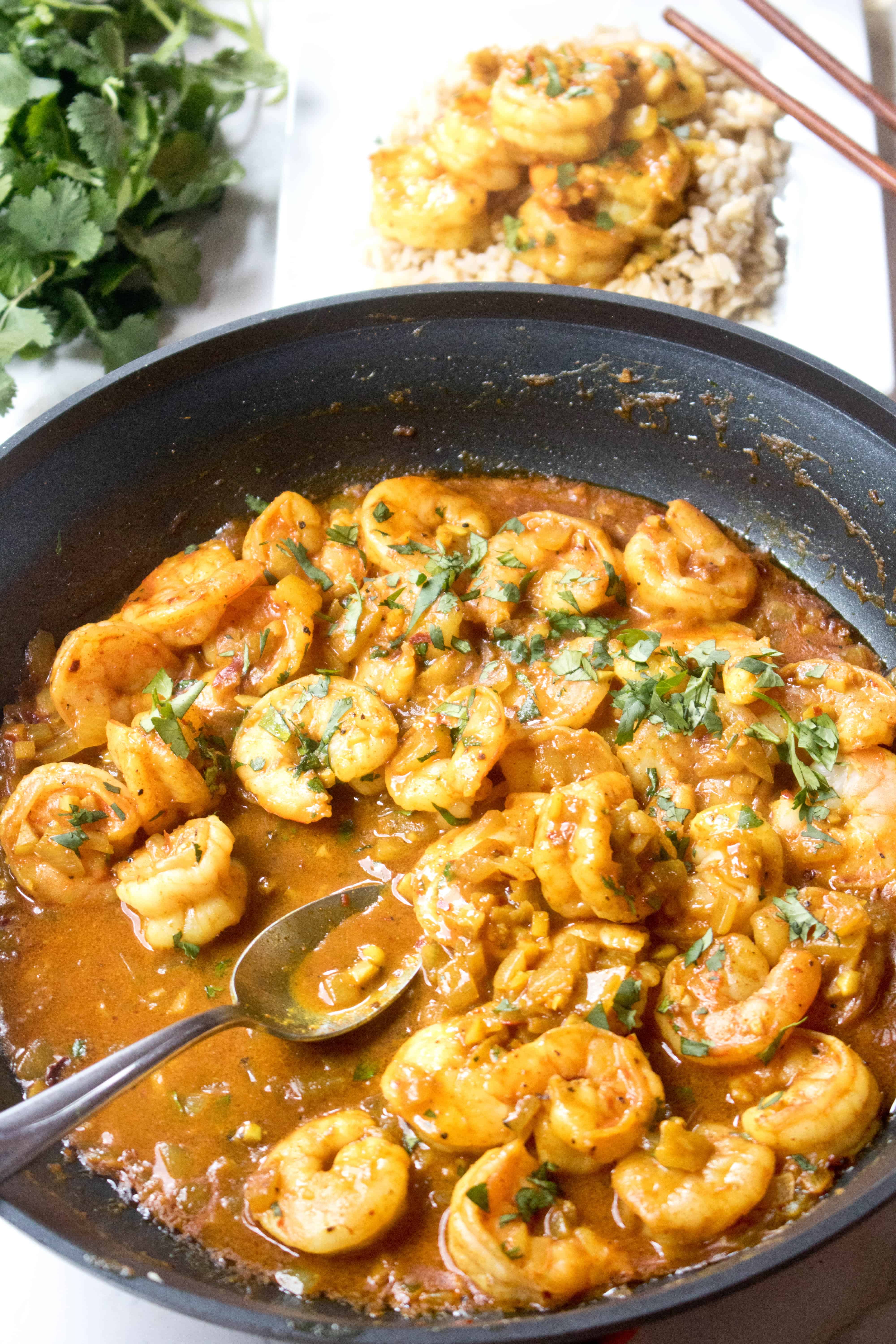 pan of curry shrimp with a spoon.