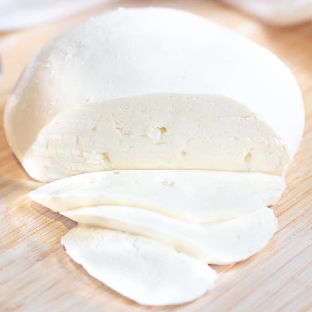 a ball of mozzarella cheese sliced on a cutting board.