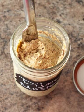 homemade Dijon mustard in a mason jar with knife.