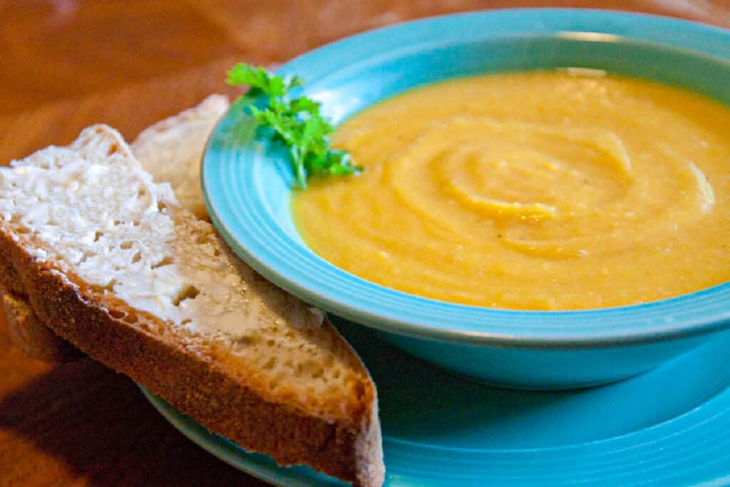 a bowl of butternut squash soup with buttered bread.