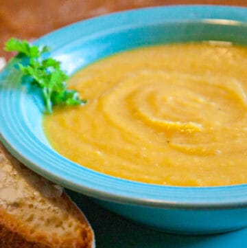 a bowl of butternut squash soup with buttered bread.