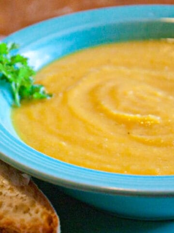 a bowl of butternut squash soup with buttered bread.