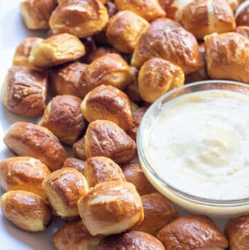 a plate of baked pretzel bites with a bowl of honey mustard sauce.