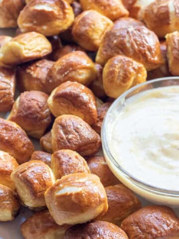 a plate of baked pretzel bites with a bowl of honey mustard sauce.