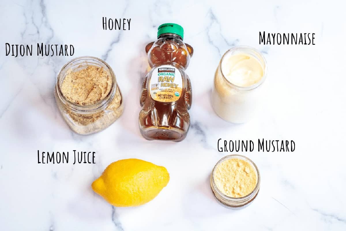 honey, Dijon, mayonnaise, lemon, and ground mustard on a counter.