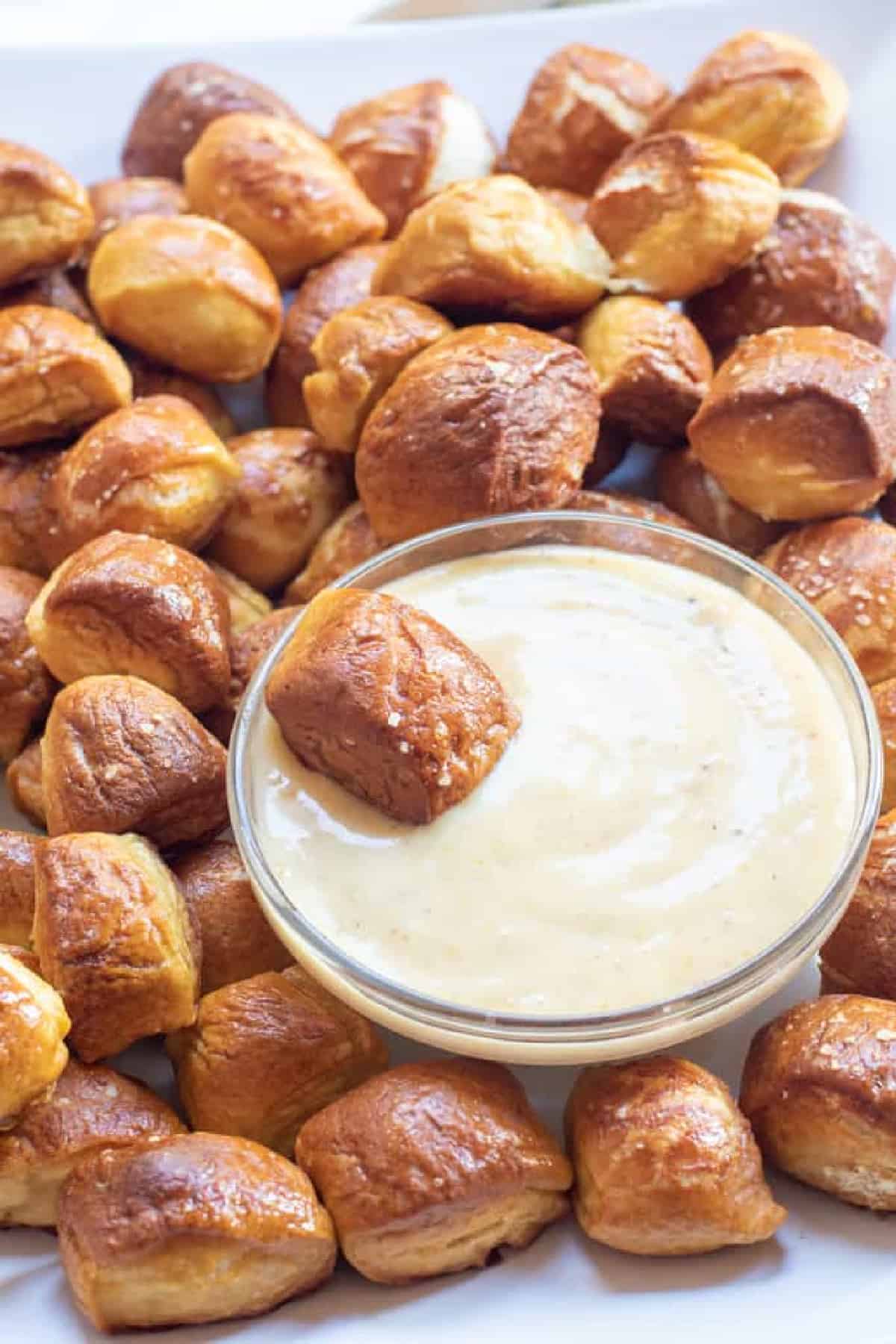 a plate of baked pretzel bites with a bowl of honey mustard sauce.
