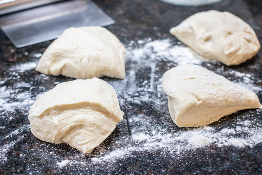 four pieces of dough on a floured counter