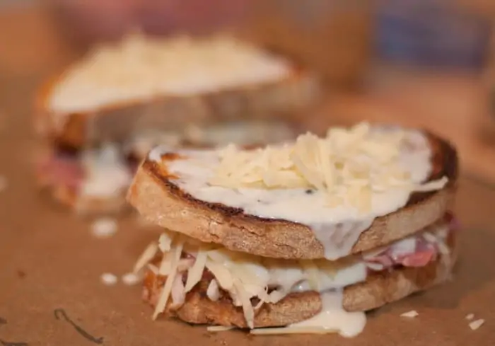 a sandwich topped with cheese and béchamel sauce.