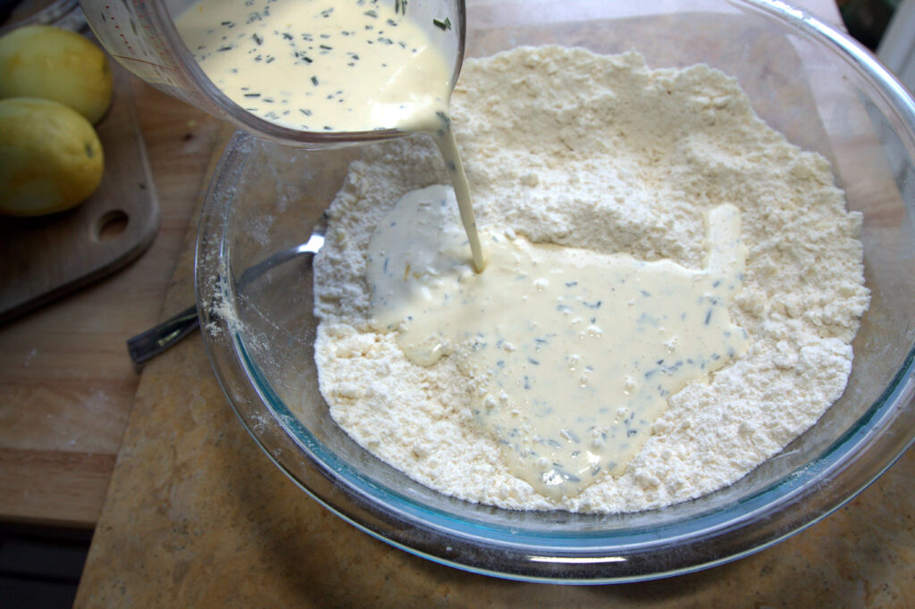 milk being poured in flour in a bowl.
