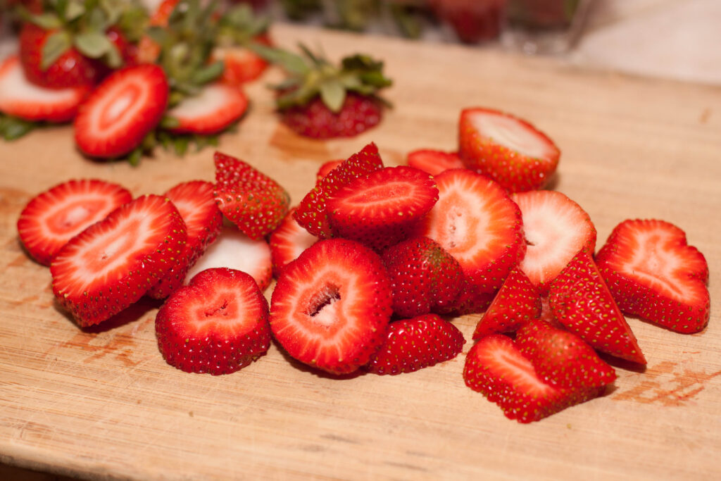 sliced fresh strawberries on a cutting board.