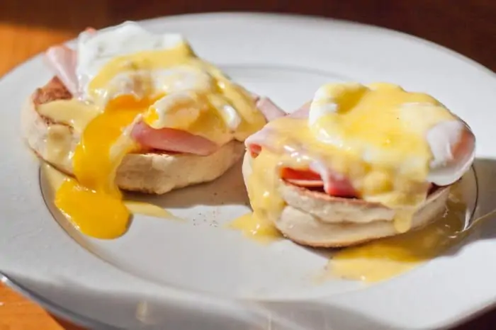 a plate with eggs benedict with hollandaise sauce.