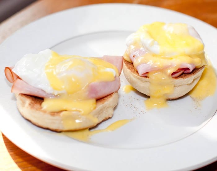 a plate with eggs benedict with hollandaise sauce.