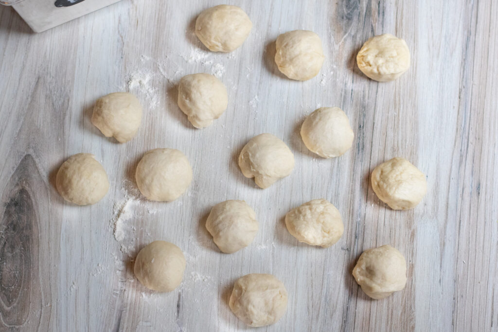 16 small doughs on a table.