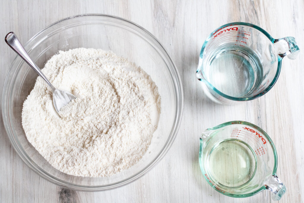a bowl of flour and pyrek jars of water and oil.