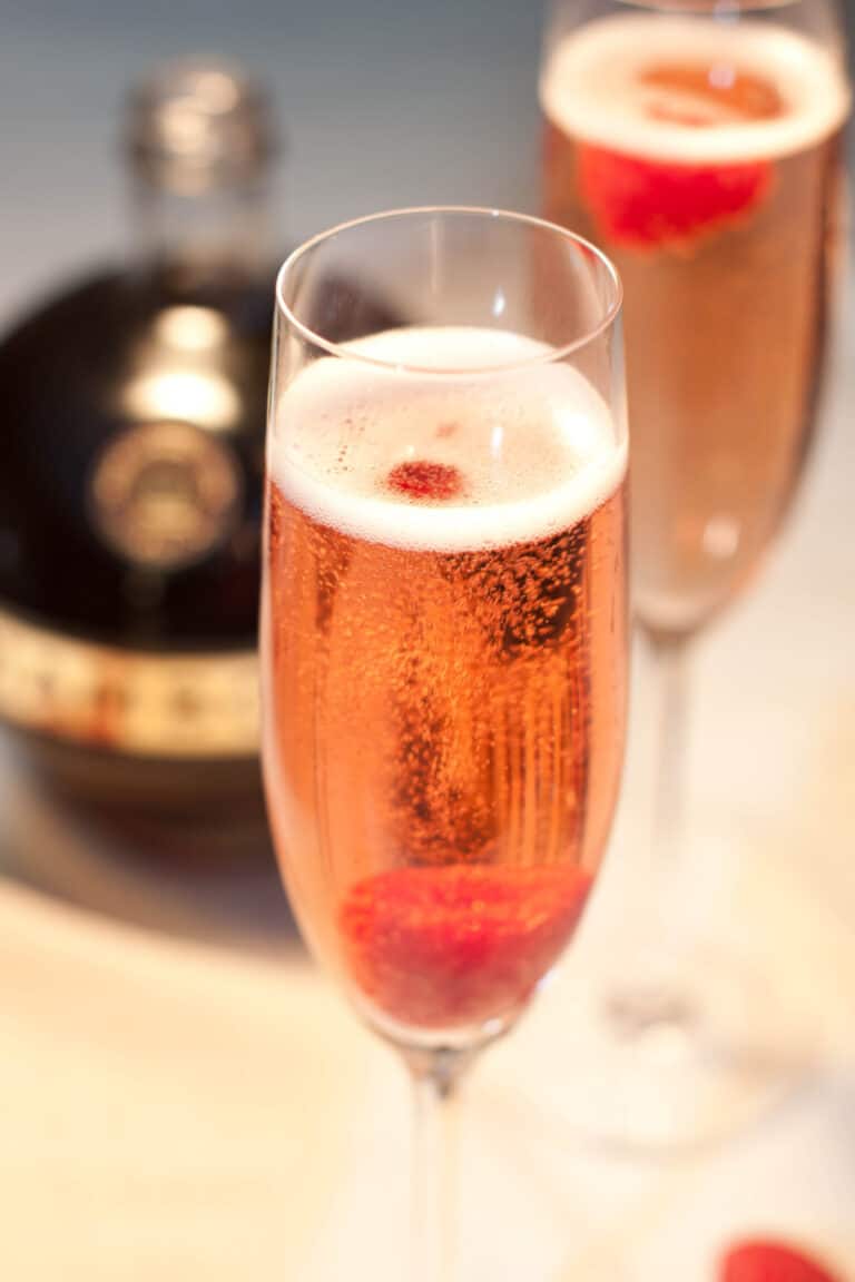 a glass of sparkling pink wine with a raspberry.