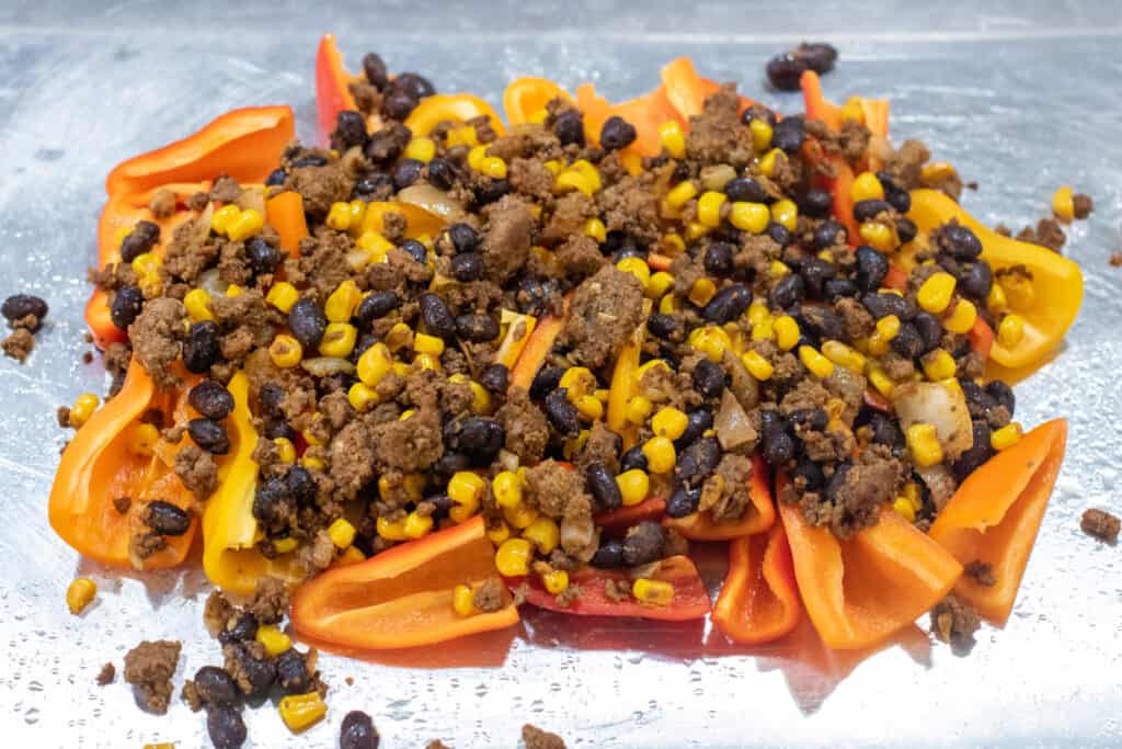 mini peppers topped with meat and beans and corn, tomatoes, and olives.