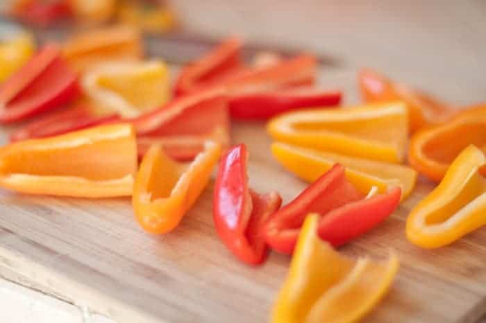 sliced and cleaned mini peppers on a cutting board.