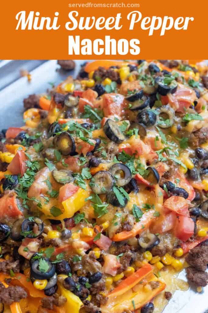 a baking sheet of mini peppers with ground beef, olives, black beans, corn, melted cheese, and fresh cilantro nachos with Pinterest pin text.