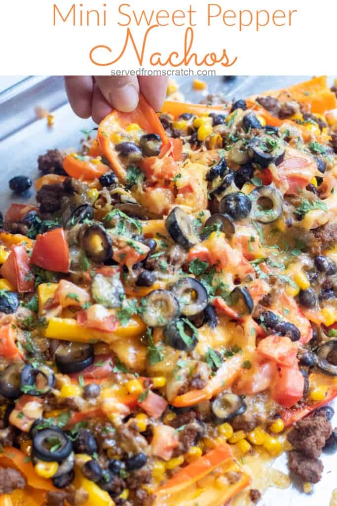 a baking sheet of mini peppers with ground beef, olives, black beans, corn, melted cheese, and fresh cilantro nachos with Pinterest pin text.