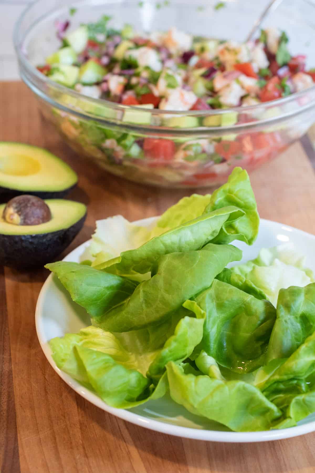 a plate of lettuce with a bowl of shrimp ceviche.