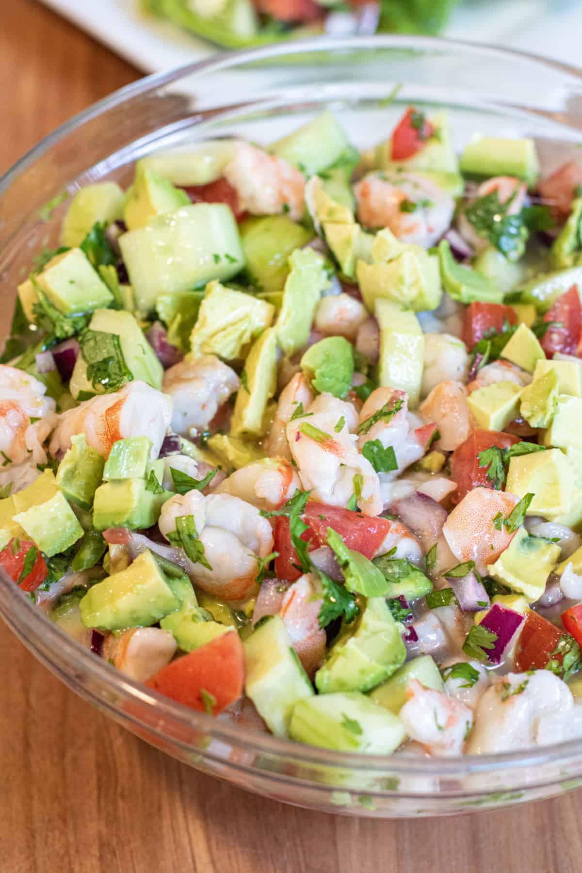 a large bowl of shrimp ceviche with cucumber, tomatoes, and onions.