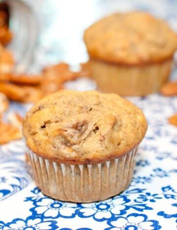 banana pecan muffin on table surrounded by pecans