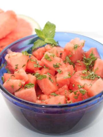 cut watermelon in a blue bowl with mint