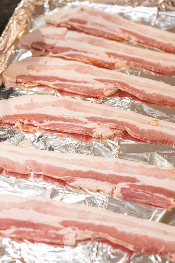 raw bacon on a foil lined baking sheet 