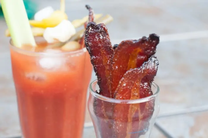 cup of candied bacon in front of a bloody mary