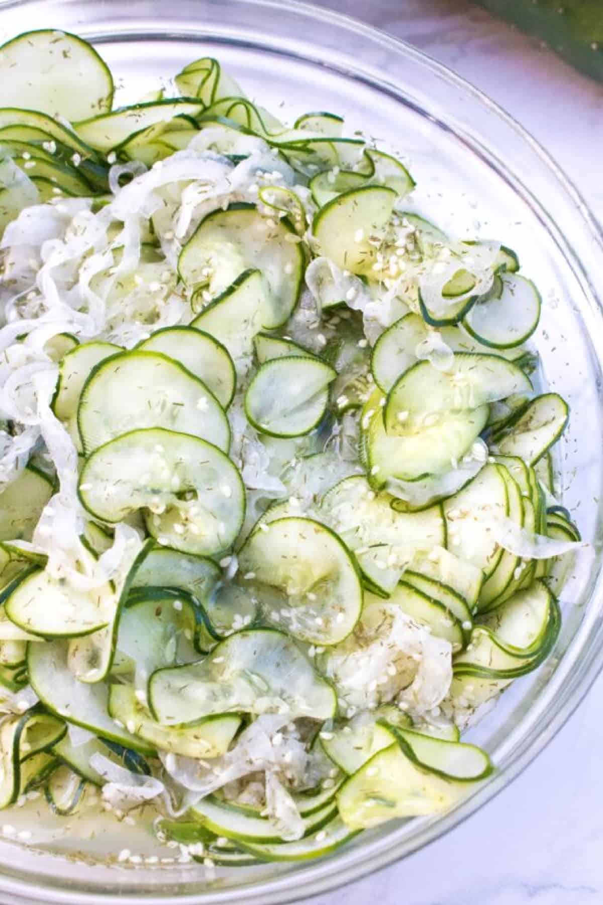 a large bowl of thinly sliced cucumbers and onions.