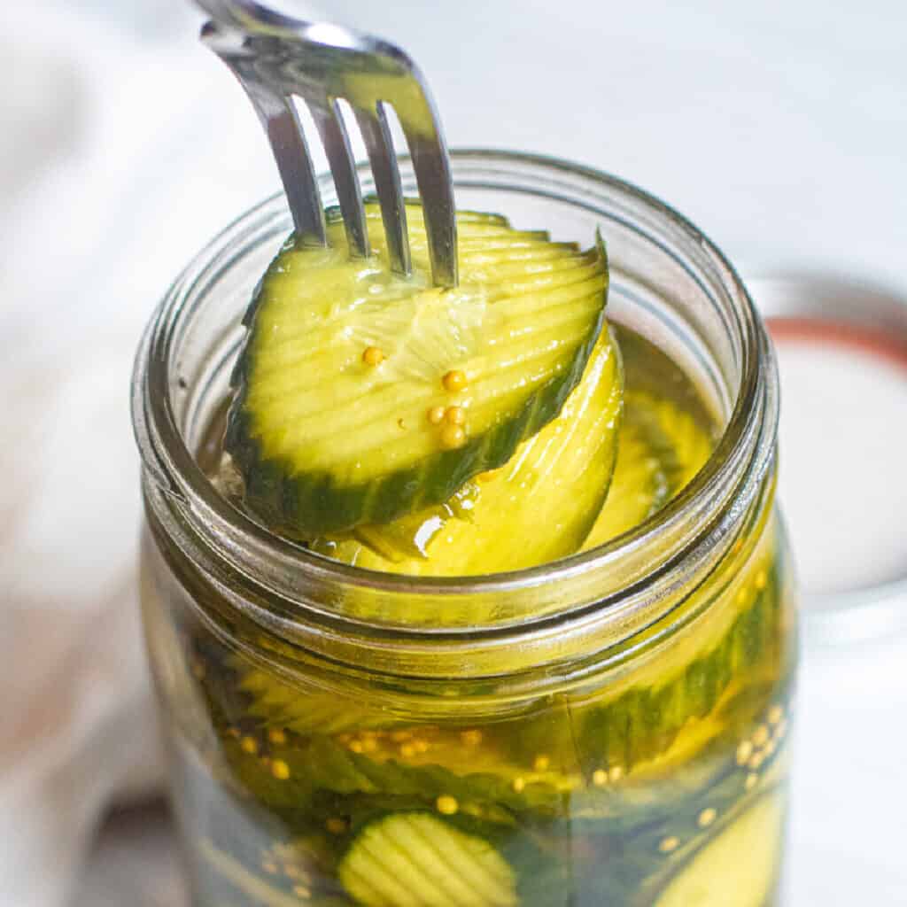 a fork taking pickles out of a jar.