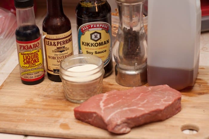 steak on cutting board with spices and seasonings behind it.