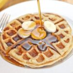 cooked banana waffles topped with sliced bananas and syrup
