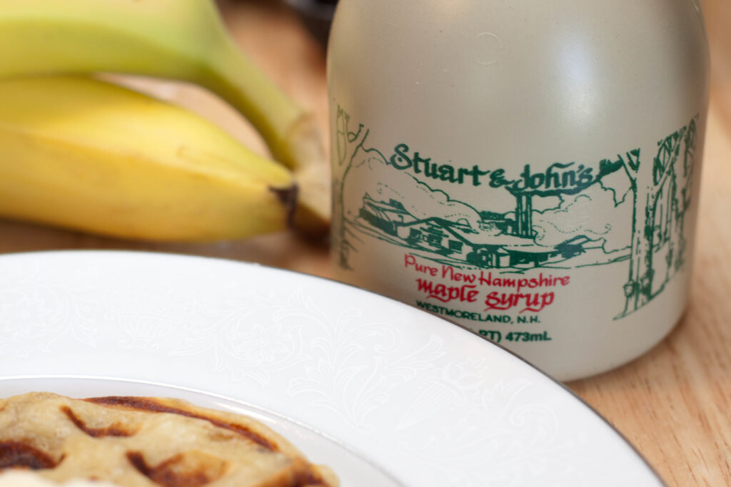 a jar of maple syrup from NH next to a plate and bananas. 