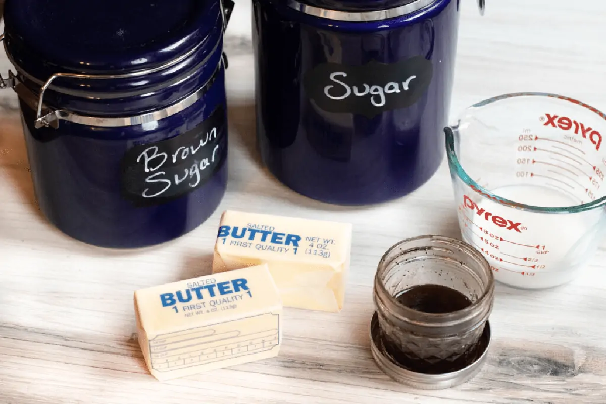 blue sugar containers, butter, vanilla, and milk on counter.