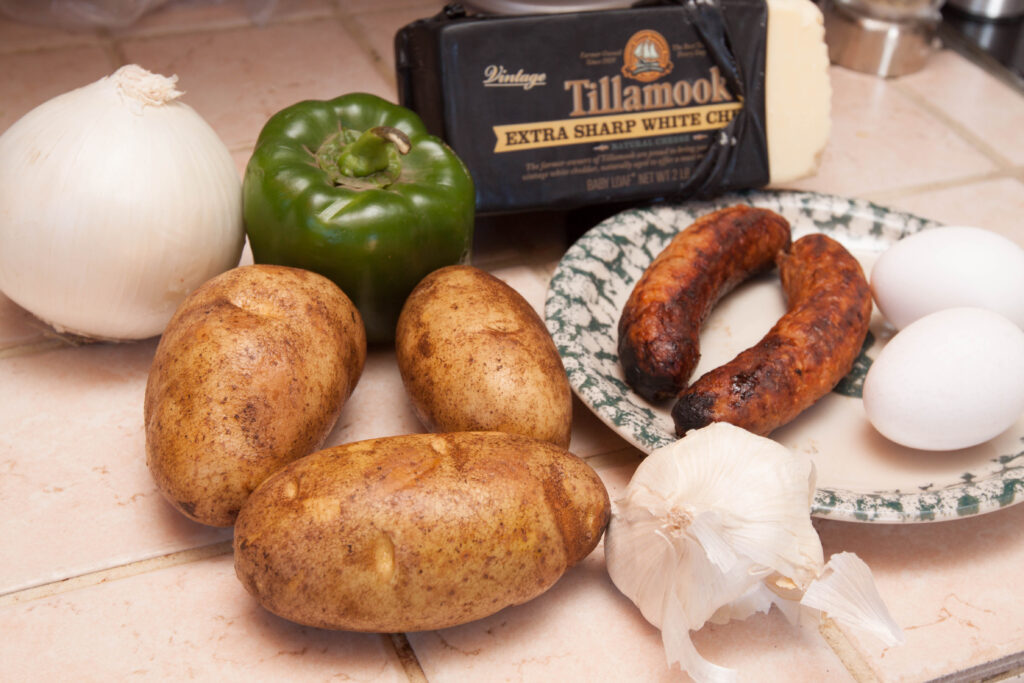 potatoes, pepper, onion, sausage, garlic, cheese on counter.