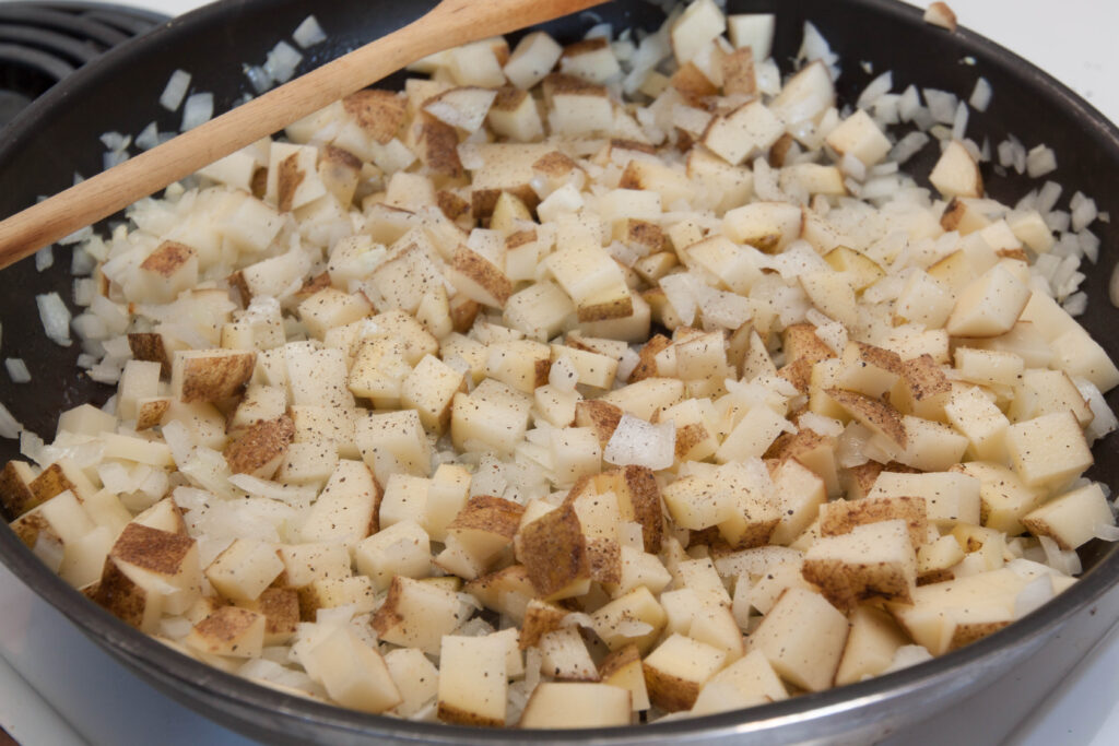 diced potatoes cooking in a large pan.