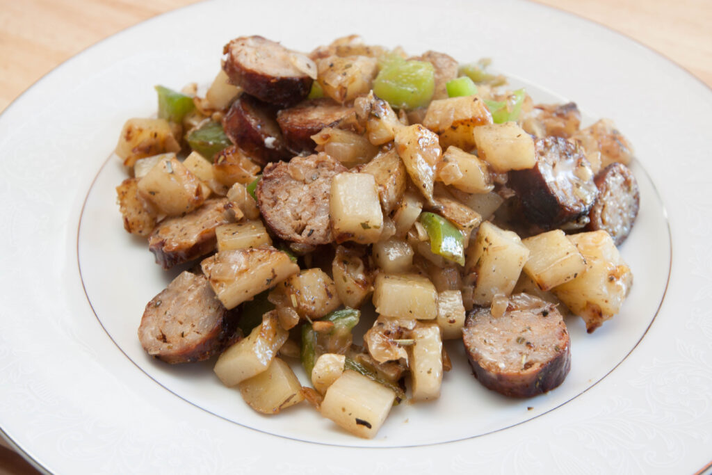 a plate of cooked potatoes, sausage, peppers.