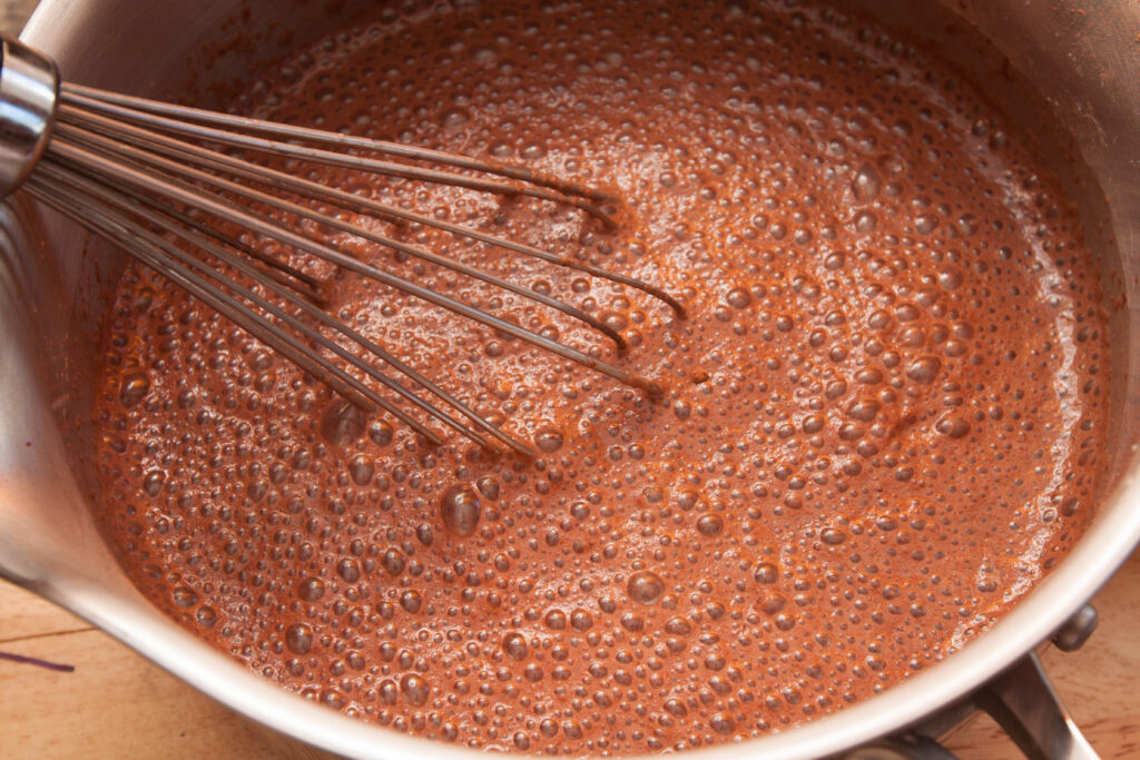 a whisk in a pot of chocolate.