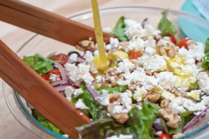 dressing being poured on a salad.