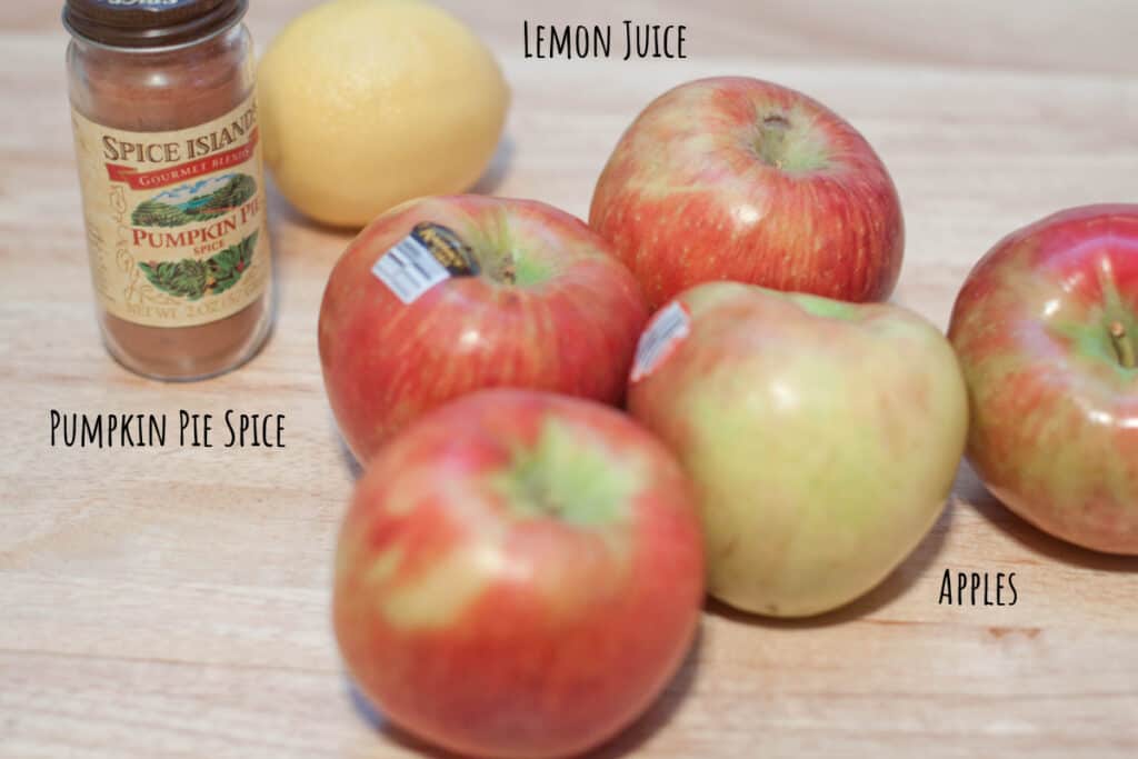 apples, pumpkin pie spice, lemon on a counter.