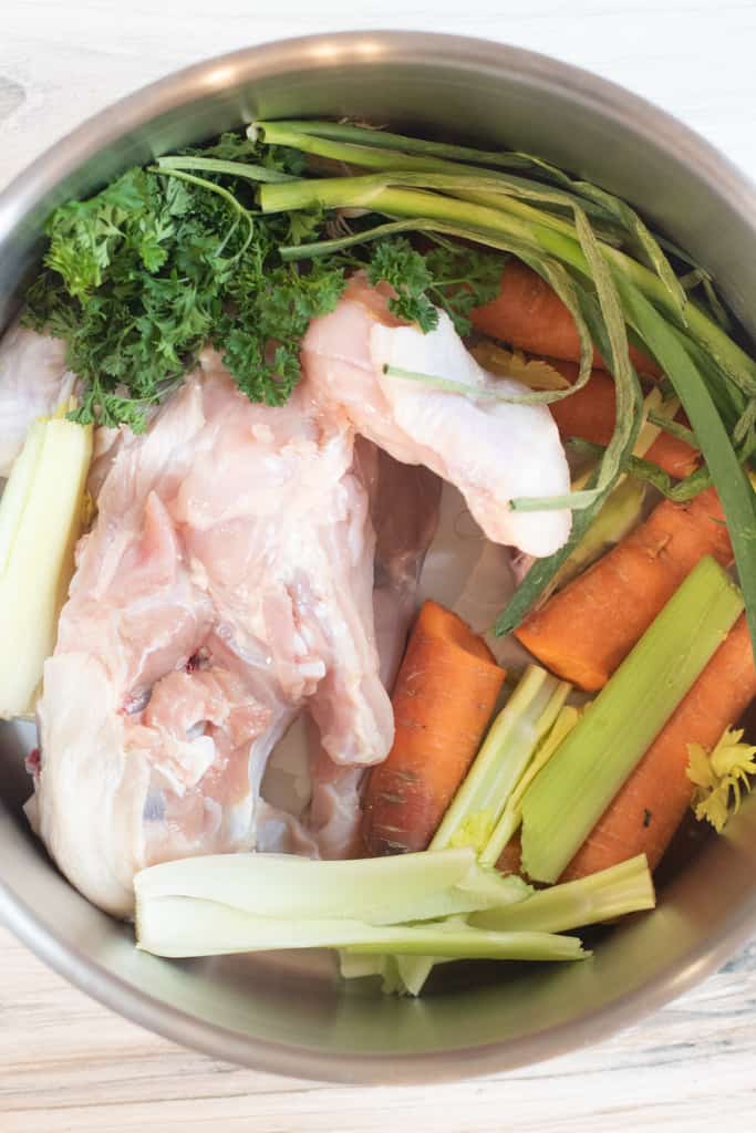 a pot with chicken carcass and vegetables.
