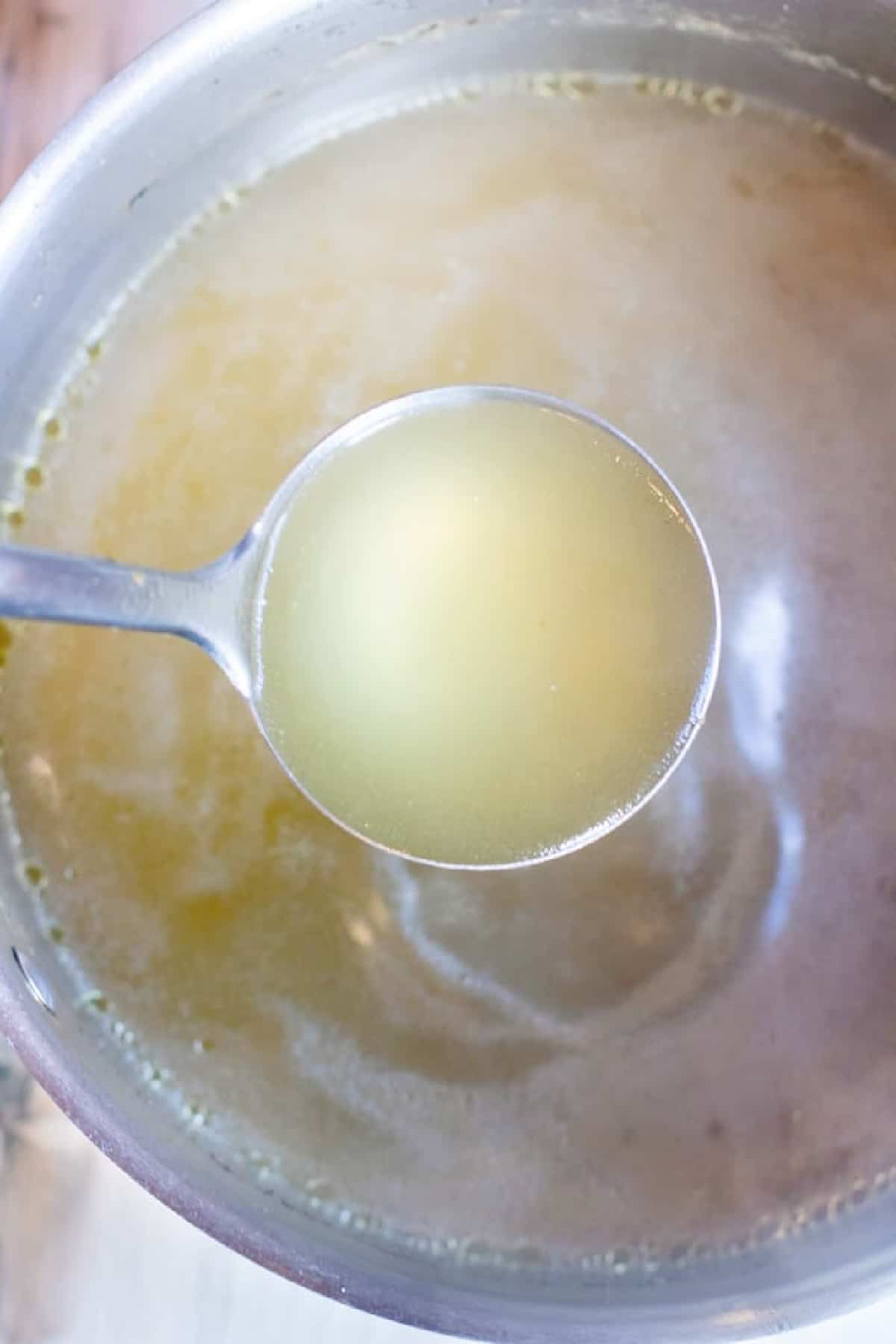 a ladle over a pot of chicken stock.