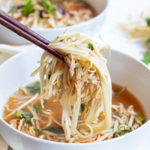 a bowl of chicken pho with chopstick holding up noodles and chicken with Pinterest pin text.