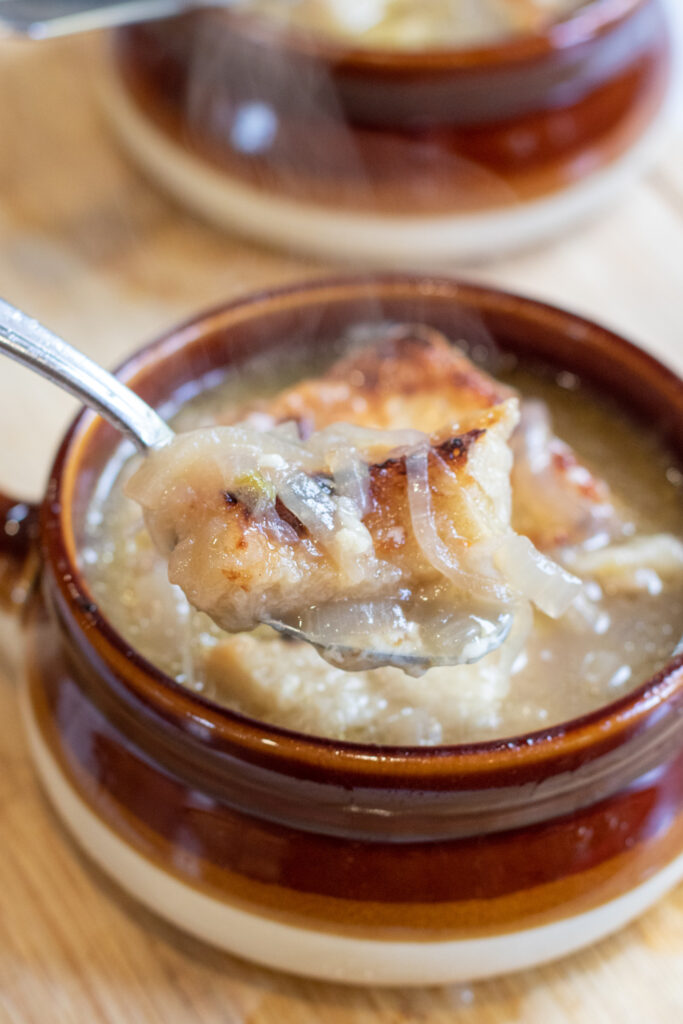 crocks of soup with spoonful of onion soup