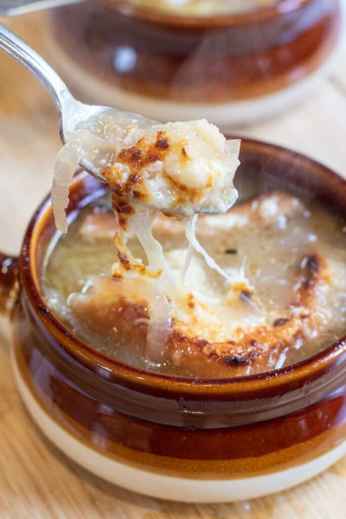 crocks of soup with spoonful of onion soup