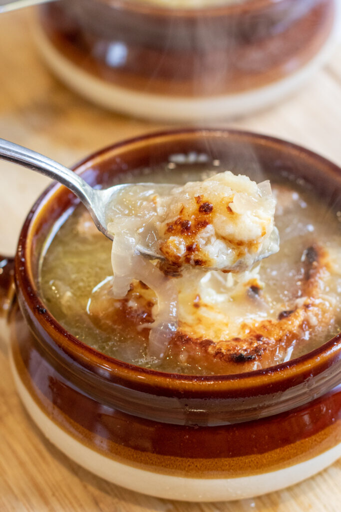 crocks of soup with spoonful of onion soup