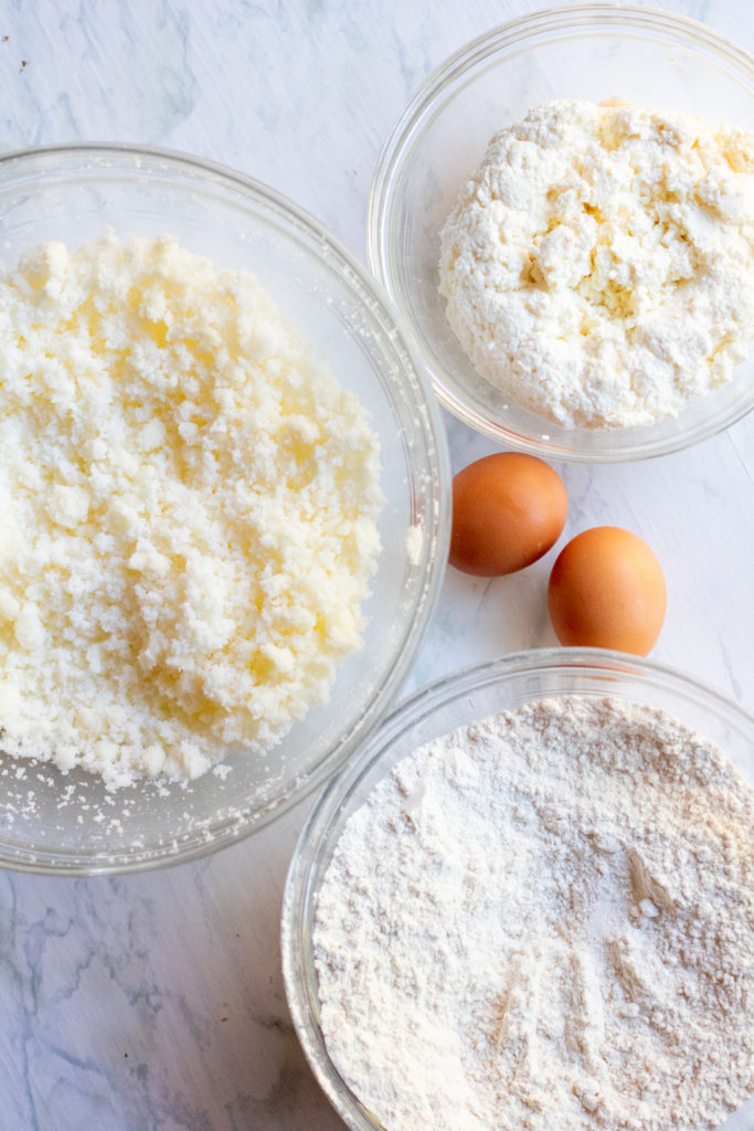 bowls of cheese and lemon and flour and sugar and eggs on counter.