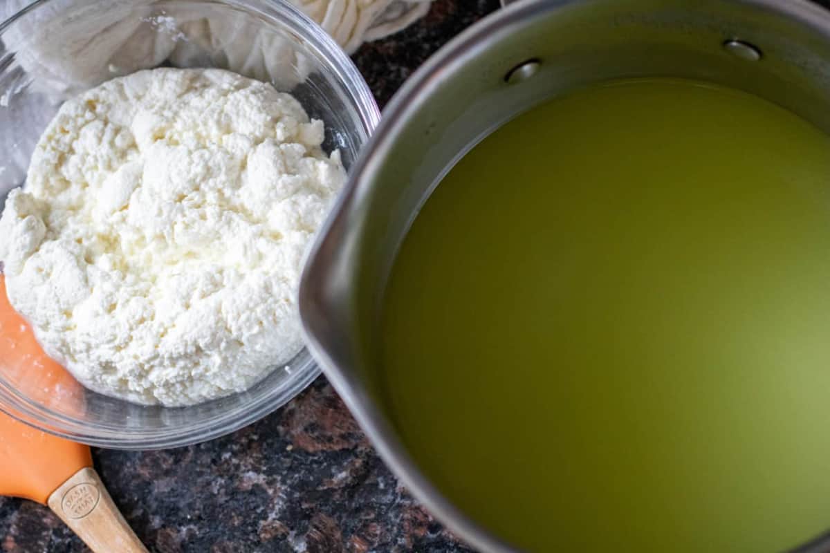 a bowl of cheese next to a pot of whey.