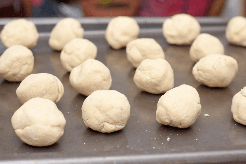 balls of masa dough lined up on a baking sheet.